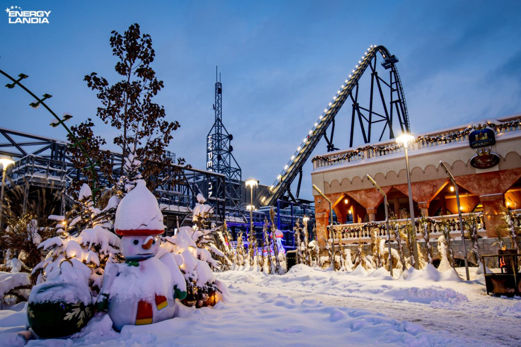 "Zimowy Hyperion Energylandia – ośnieżony krajobraz parku rozrywki z rollercoasterem Hyperion i świątecznymi ozdobami."