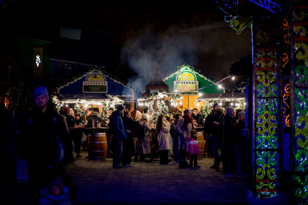 "Jarmark zimowy Energylandii nocą – goście spacerujący między świątecznymi stoiskami i ogrzewającymi lampami w Winter Kingdom."