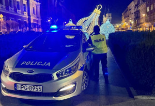 "Policjant stoi przy radiowozie"